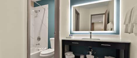 Un baño moderno con bañera, inodoro y tocador con espejo.