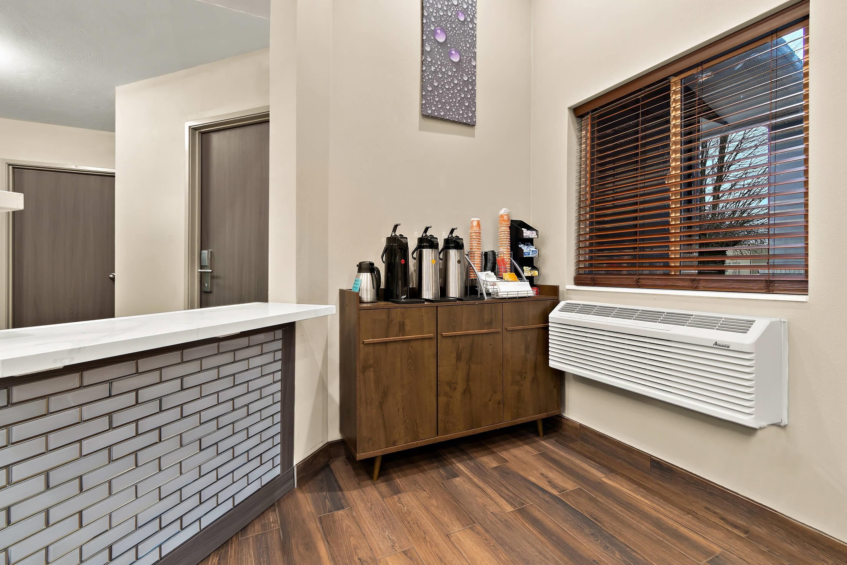 A reception area with a brick wall, wooden cabinets, a white counter, and a window with blinds.