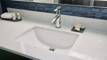 A bathroom sink with a chrome faucet, a towel, and toiletries on the countertop.