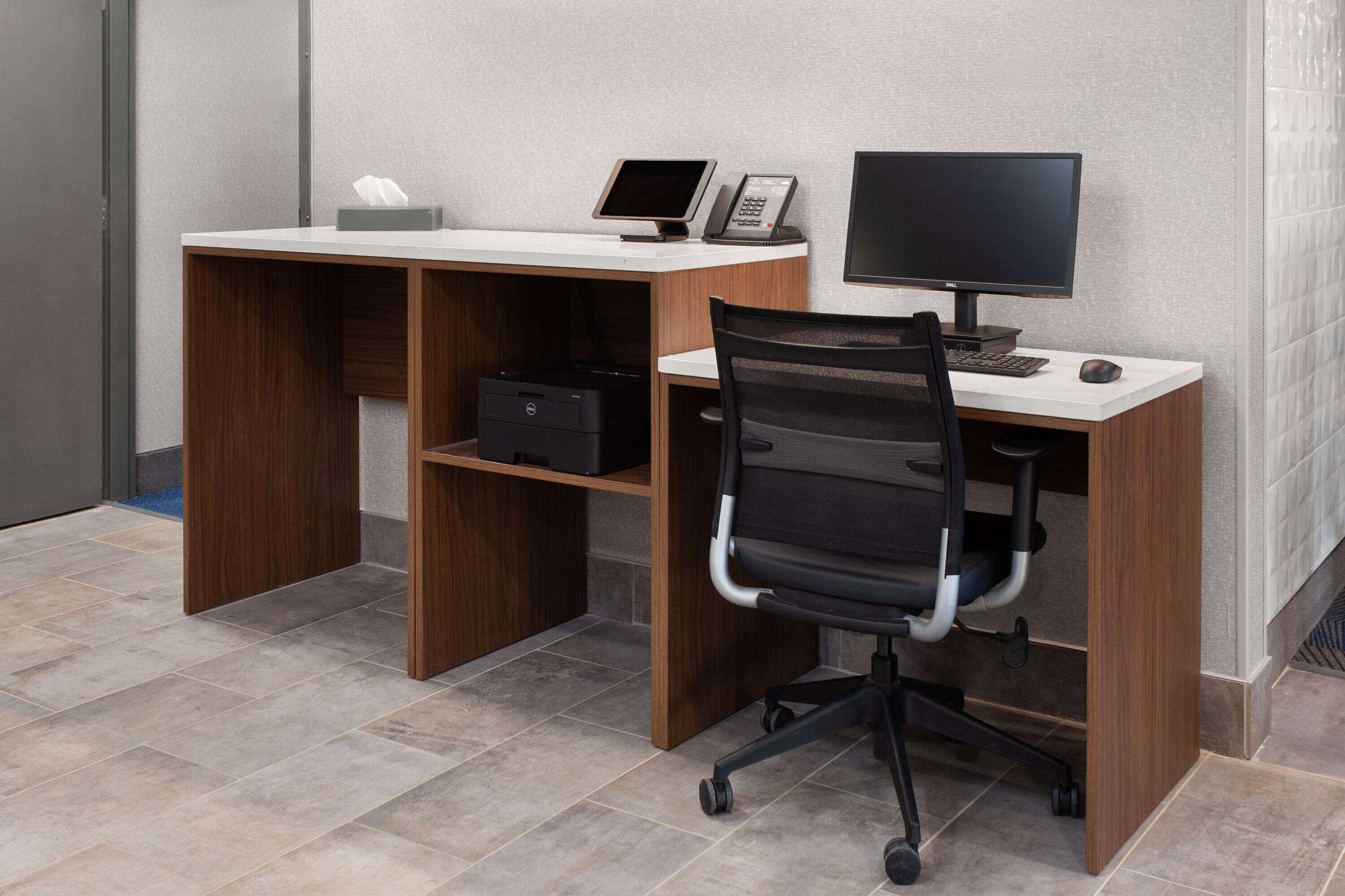 Un escritorio moderno con una computadora, un teléfono y una silla.