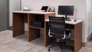 Un escritorio moderno con una computadora, un teléfono y una silla.