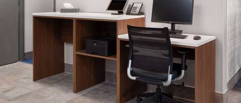 A modern office desk with a computer, a phone, and a chair.
