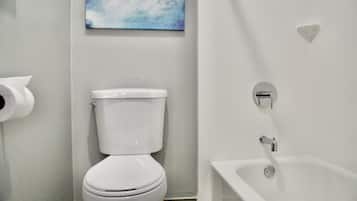A bathroom with a toilet, a bathtub, and a toilet paper holder.