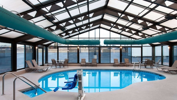 Una piscina interior con techo de cristal, sillones de descanso y un tobogán.