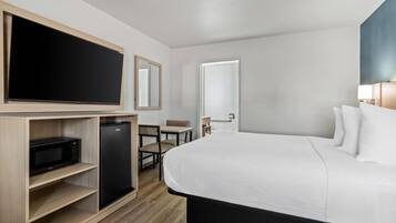 Et hotelværelse med seng, fjernsyn, minibar, skrivebord og stol.