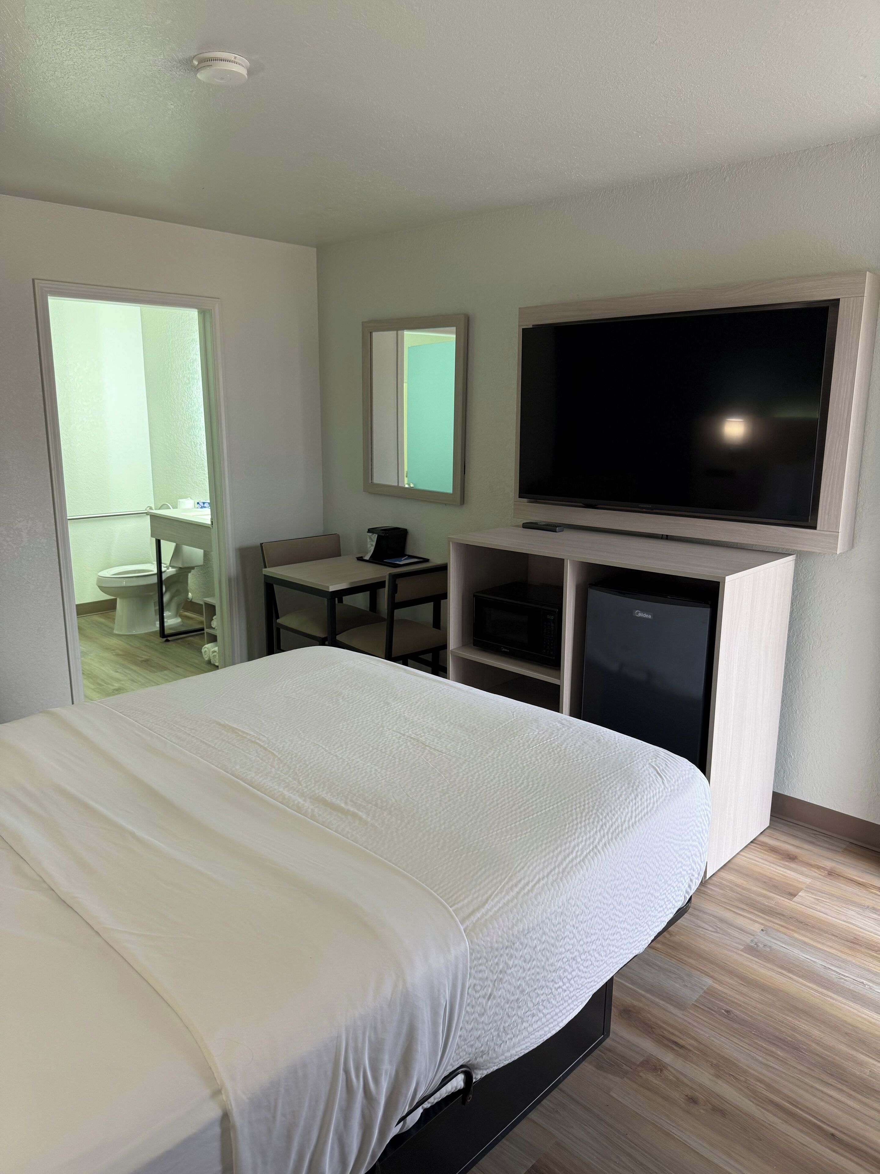 Una habitación de hotel con una cama, un escritorio, un televisor y un microondas.