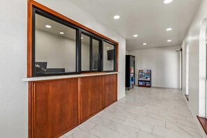 A reception area with a wooden reception desk, a large mirror, and a magazine rack. - Rodeway Inn Muskogee (Muskogee)