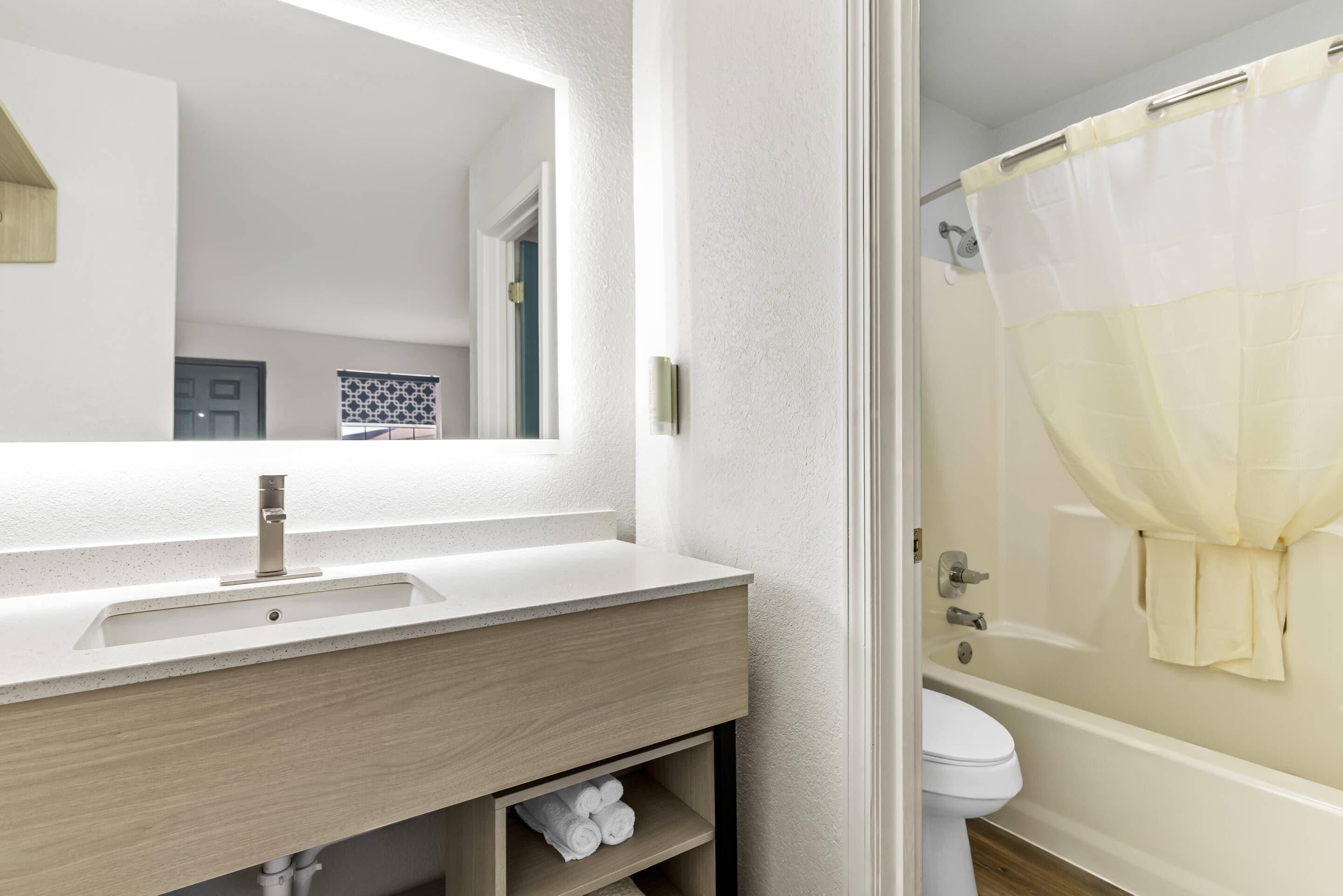 Une salle de bain avec un meuble-lavabo en bois, un lavabo, des toilettes et un rideau de douche.