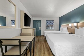 A hotel room with a bed, a desk, a chair, a TV, and a door.