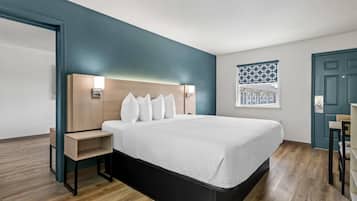Una habitación de hotel moderna con una cama grande, mesitas de noche empotradas y un cabecero con iluminación integrada.