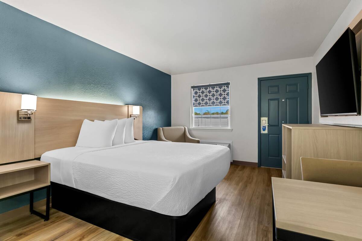 A modern hotel room with a large bed, bedside tables, a desk, and a chair.
