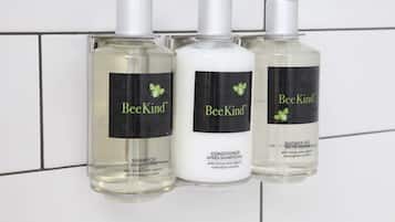 Tres botellas de productos BeeKind: champú, acondicionador y gel de ducha.
