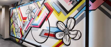 Un couloir orné d’une fresque murale abstraite aux couleurs vives.
