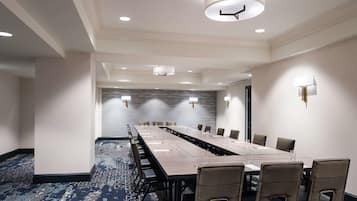 A conference room with a long table, chairs, and a carpeted floor.
