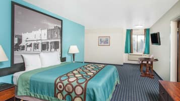 Een hotelkamer met een bed, een bureau, een stoel, een televisie en een raam met gordijnen.