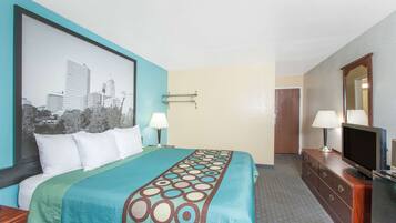 Habitación de hotel con cama, televisión, cómoda y un cuadro de un paisaje urbano en la pared.