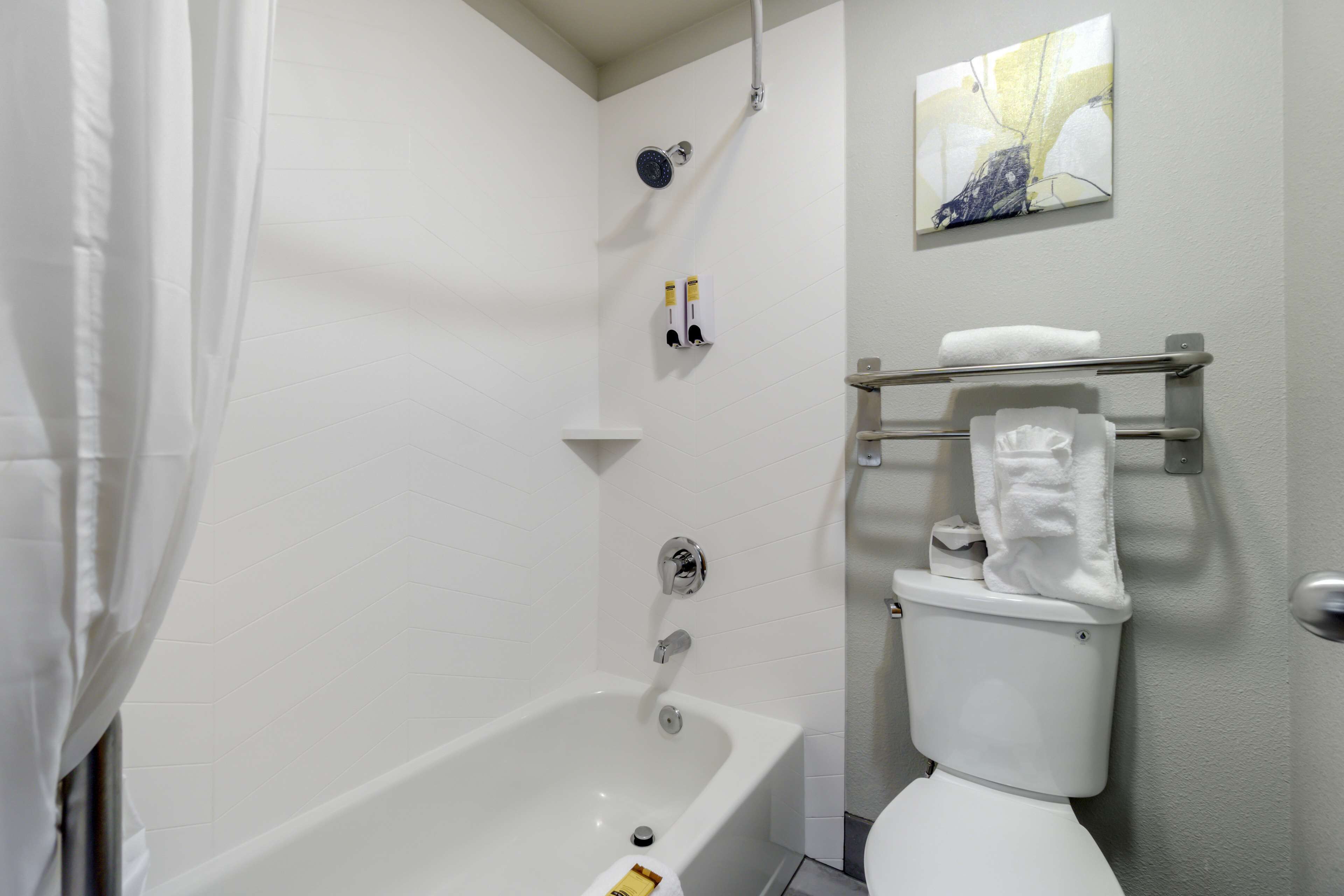 A bathroom with a bathtub, toilet, and a towel rack.