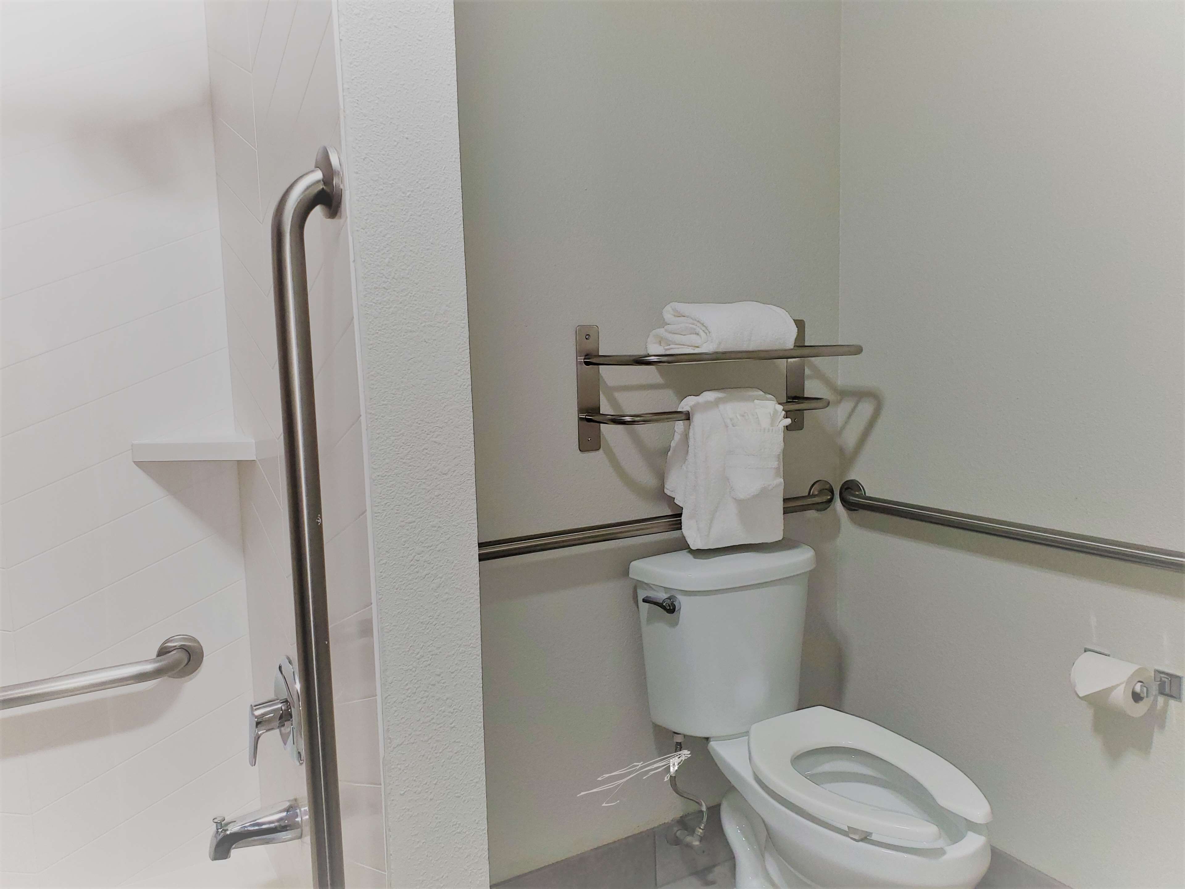 A bathroom with a white toilet, a towel rack, and a grab bar.
