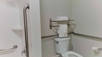 A bathroom with a white toilet, a towel rack, and a grab bar.