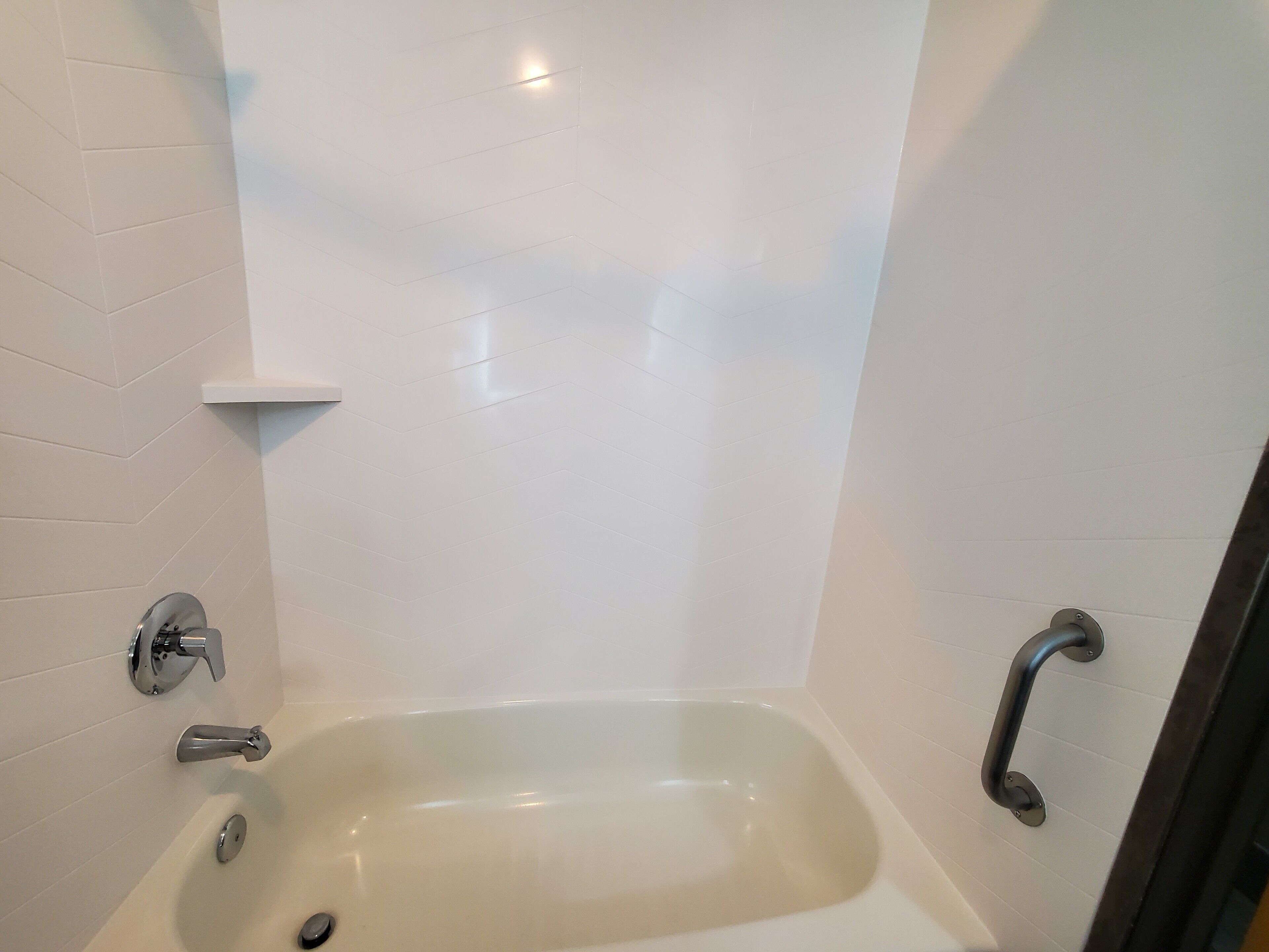 A modern bathroom with a freestanding bathtub, a handheld showerhead, and a grab bar.