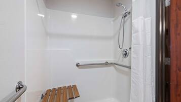 A shower area with a white bathtub, a wooden bench, a grab bar, and a showerhead.