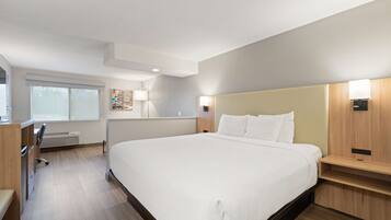A modern hotel room with a large bed, bedside tables, a desk, and a chair.