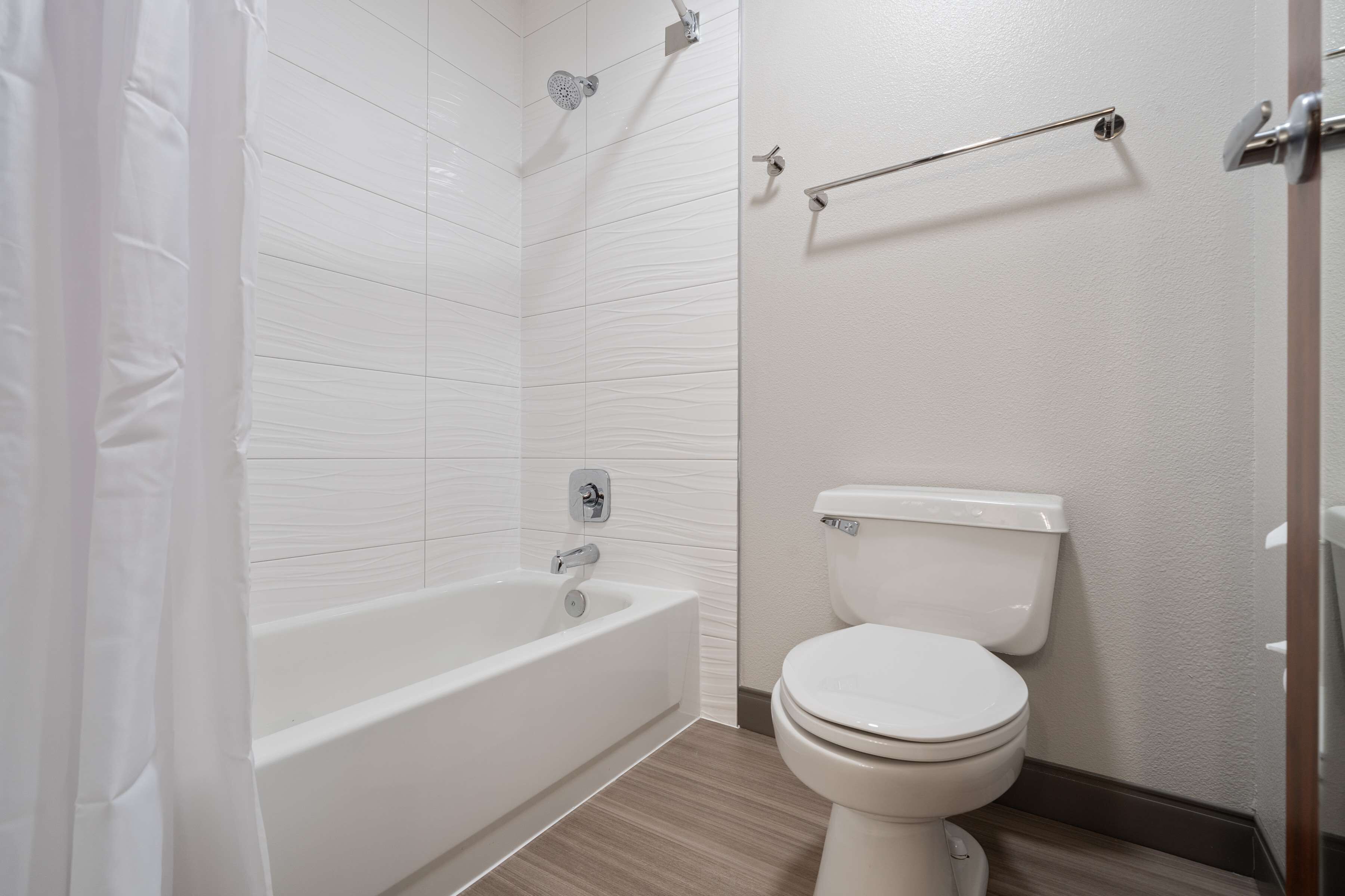 Un baño moderno con una bañera blanca, inodoro y ducha.