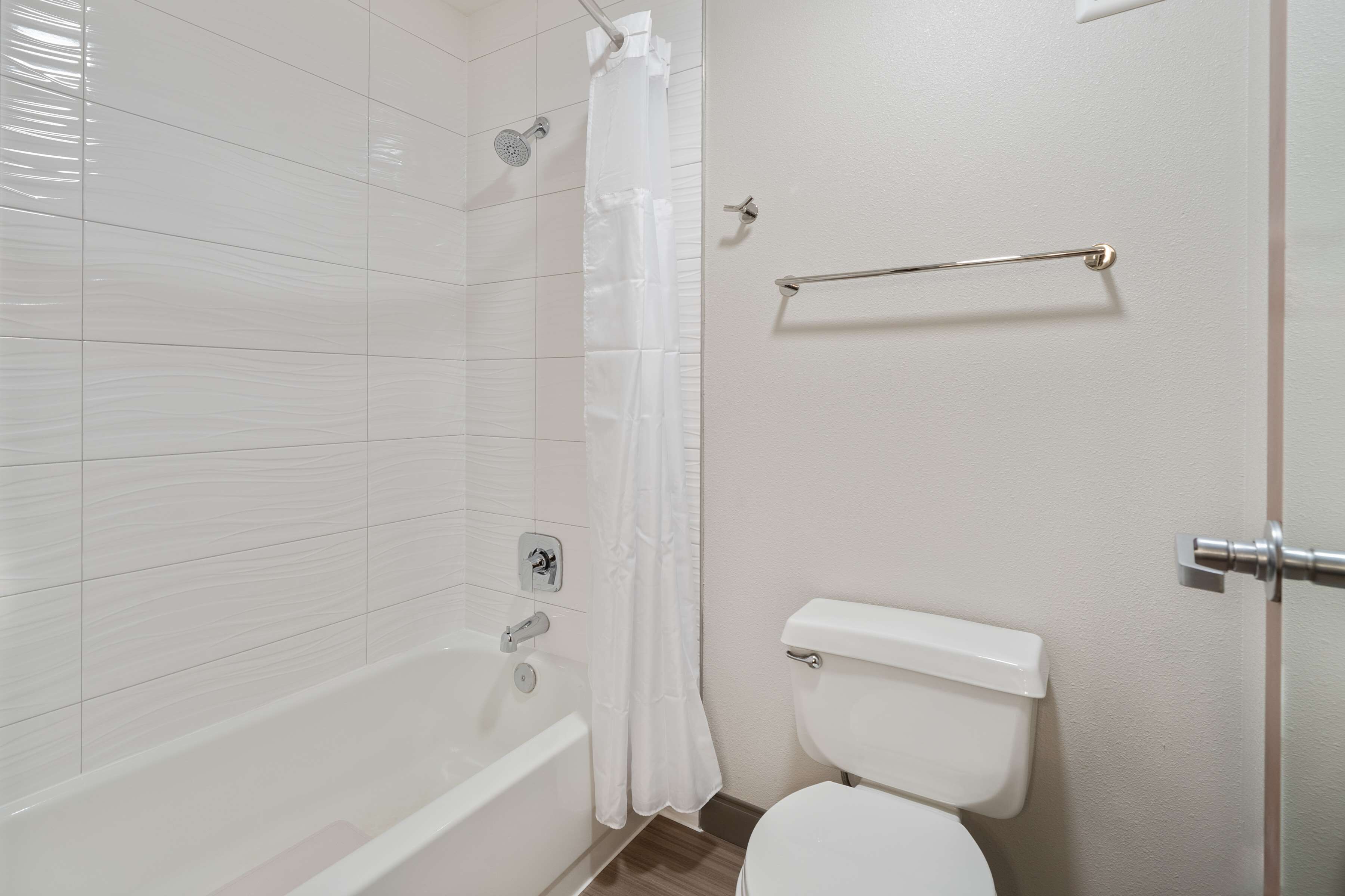 A bathroom with a white bathtub, a toilet, and a shower curtain.