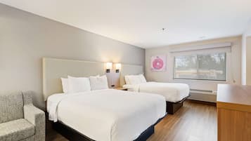 Una habitación de hotel moderna con dos camas, un sofá y un ventanal con persianas.