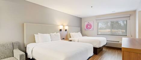 A modern hotel room with two beds, a sofa, and a large window with blinds.