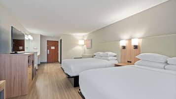 A hotel room with two beds, a desk with a mirror, and bedside lamps.