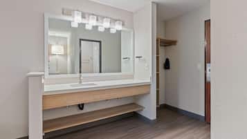 Une salle de bain avec un grand miroir, un meuble-lavabo et une étagère en bois.