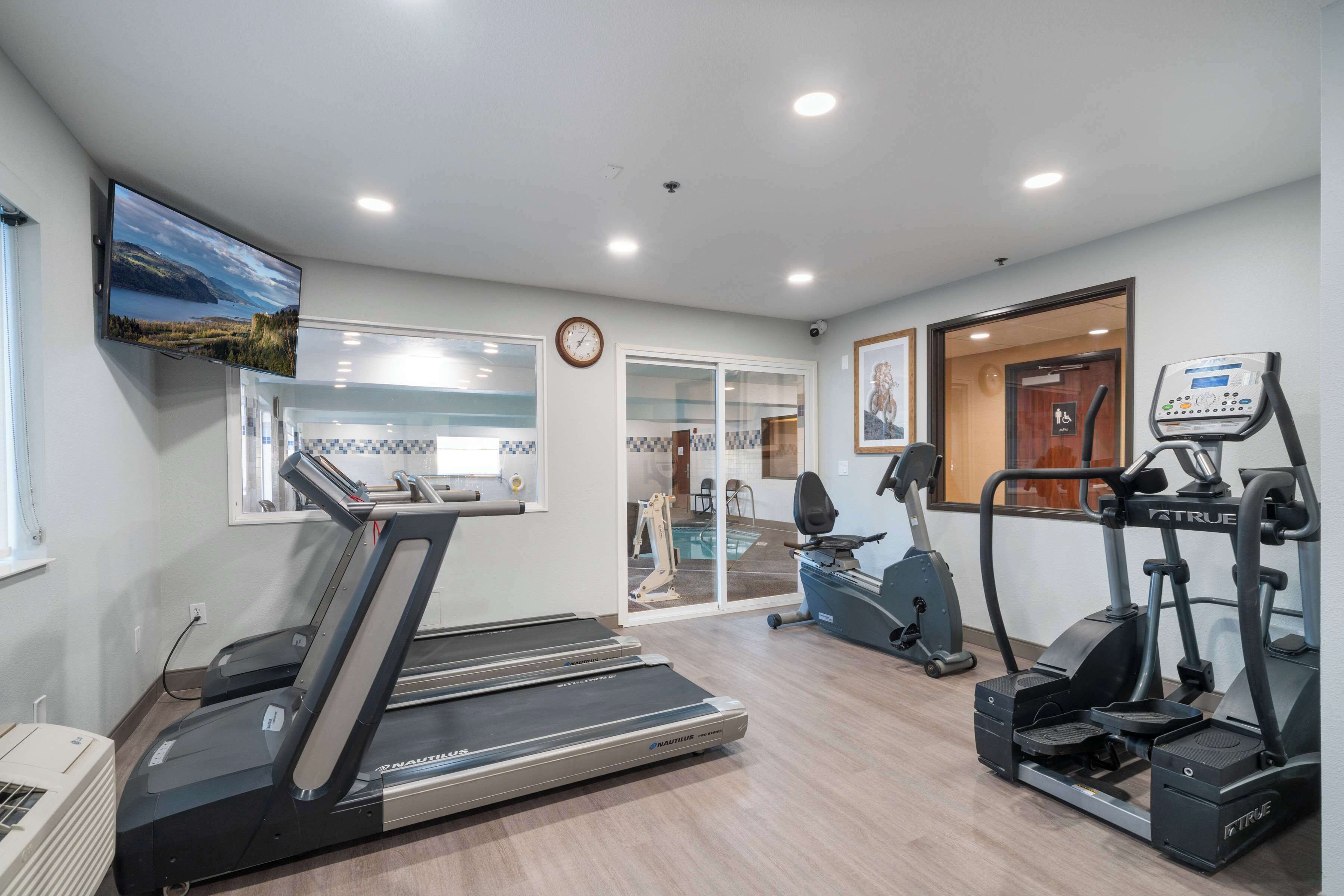 Un gimnasio con cintas de correr, elíptica y bicicleta estática.