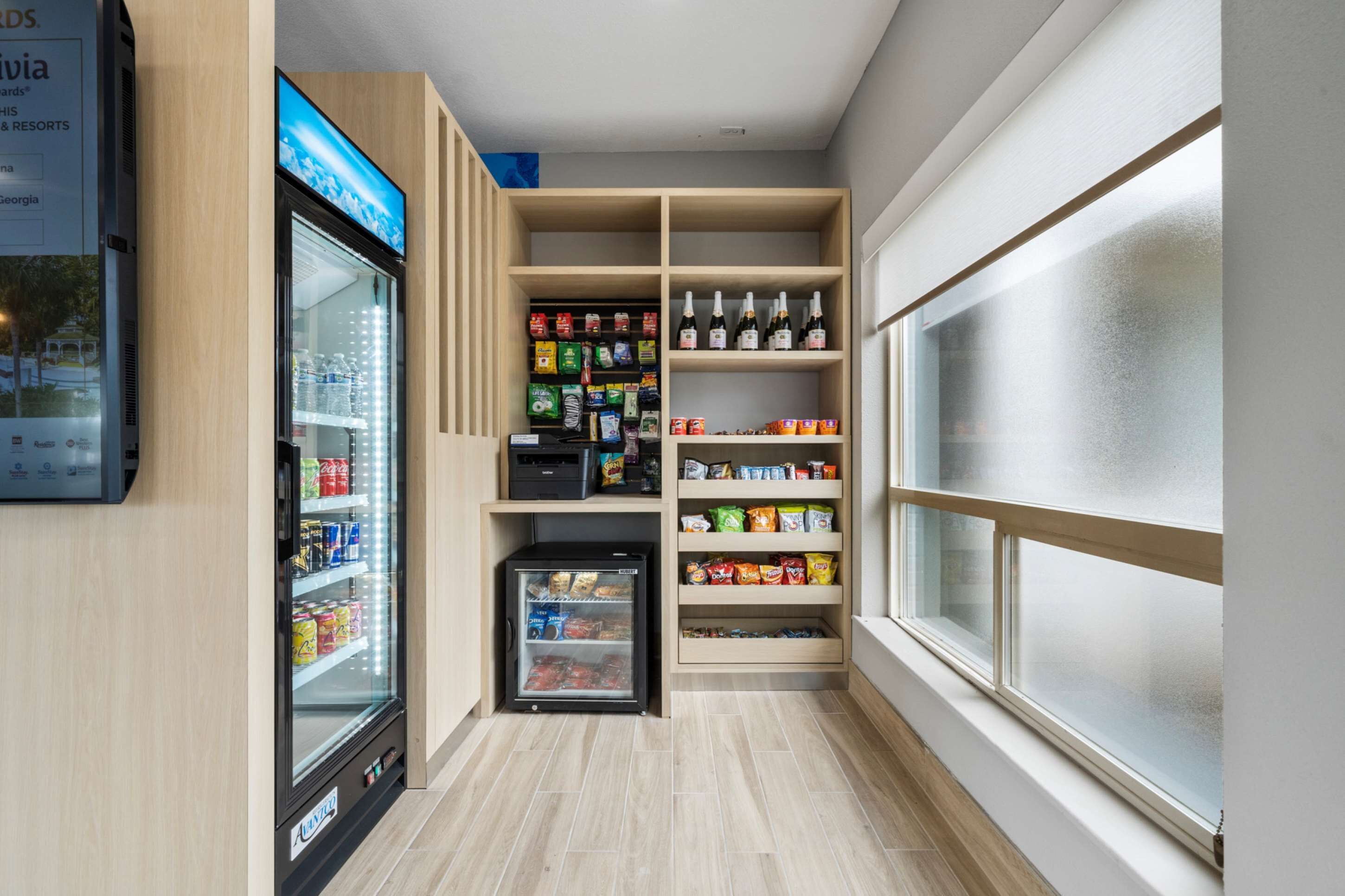A narrow hallway with a refrigerated beverage dispenser, snack shelves, and a small refrigerator.