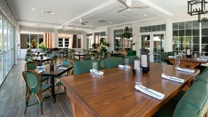 A spacious restaurant with high ceilings, large windows, and a variety of seating options including tables and chairs. - Ohio University Inn & Conference Center (Athens)