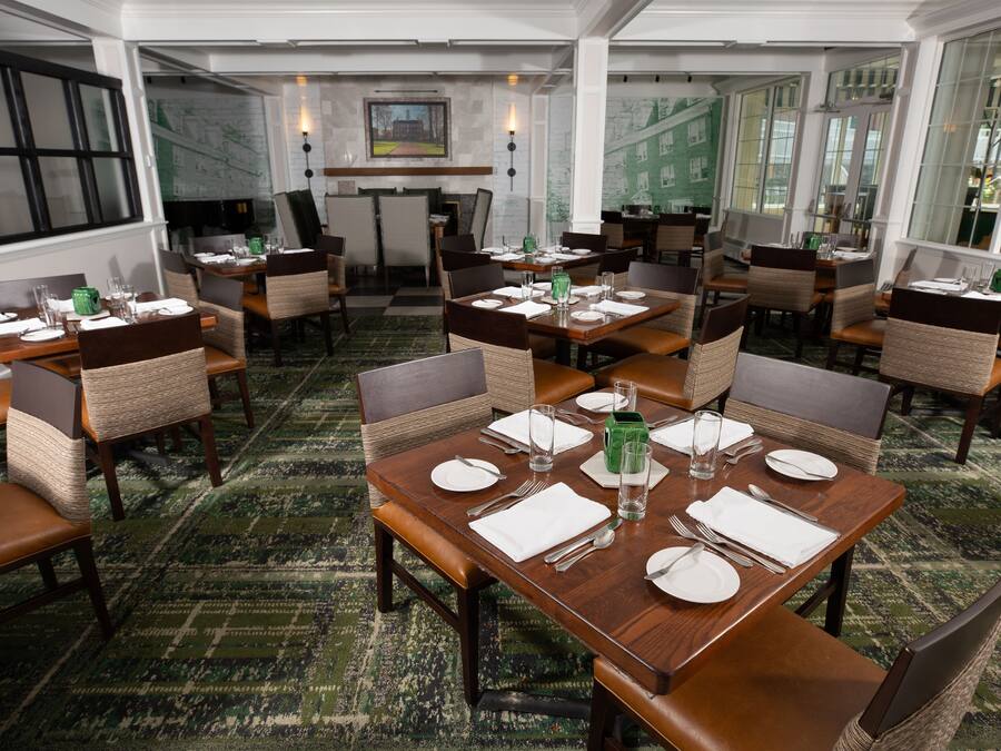 Un restaurante con varias mesas dispuestas para comer, con sillas de mimbre y mesas de madera.