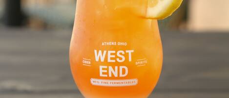 A glass of West End cider on a wooden table.