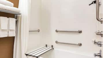 A bathroom with a white bathtub, grab bars, and a towel rack.