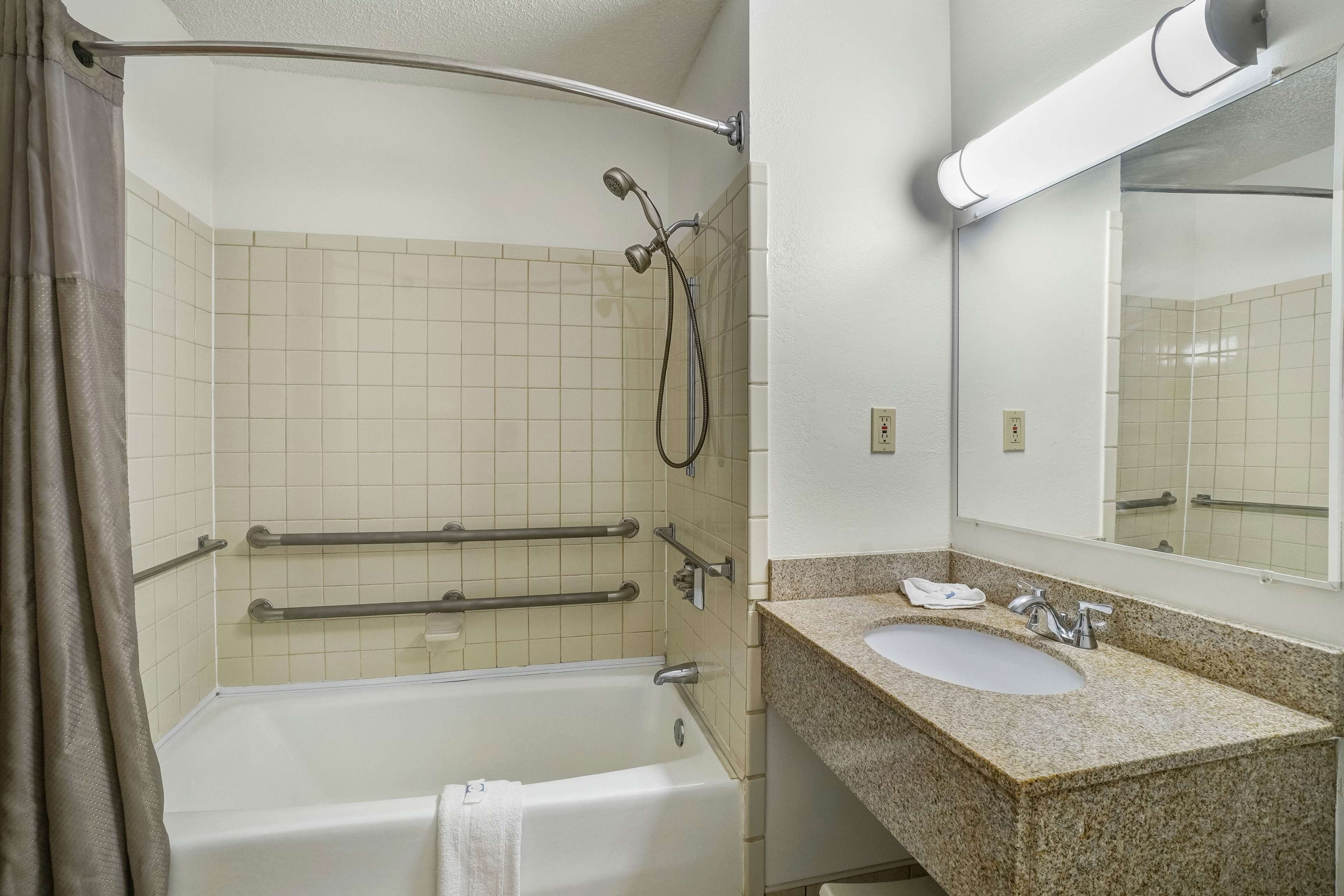 A bathroom with a bathtub, a sink, a mirror, and a shower with a handheld showerhead.