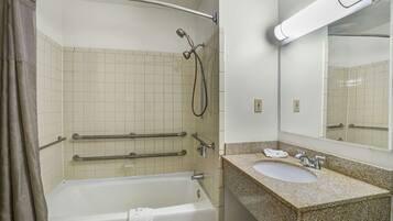 A bathroom with a bathtub, a sink, a mirror, and a shower with a handheld showerhead.