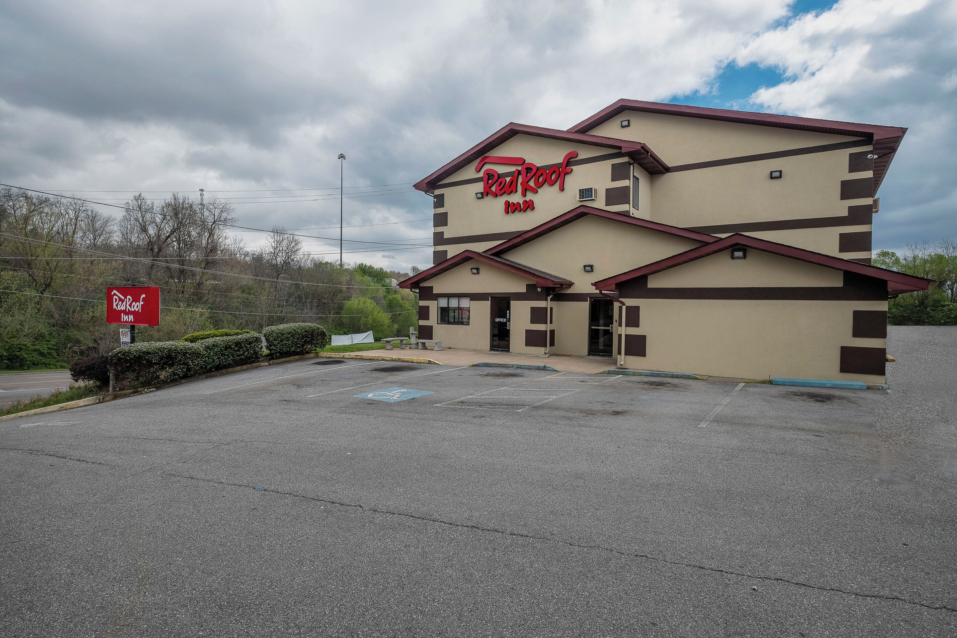 A Red Roof Inn with a two-story building, a parking lot, and a signboard.
