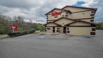 A Red Roof Inn with a two-story building, a parking lot, and a signboard.