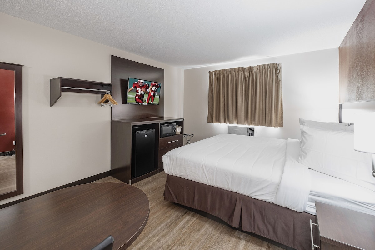 Una habitación de hotel con cama, escritorio, televisor y armario.