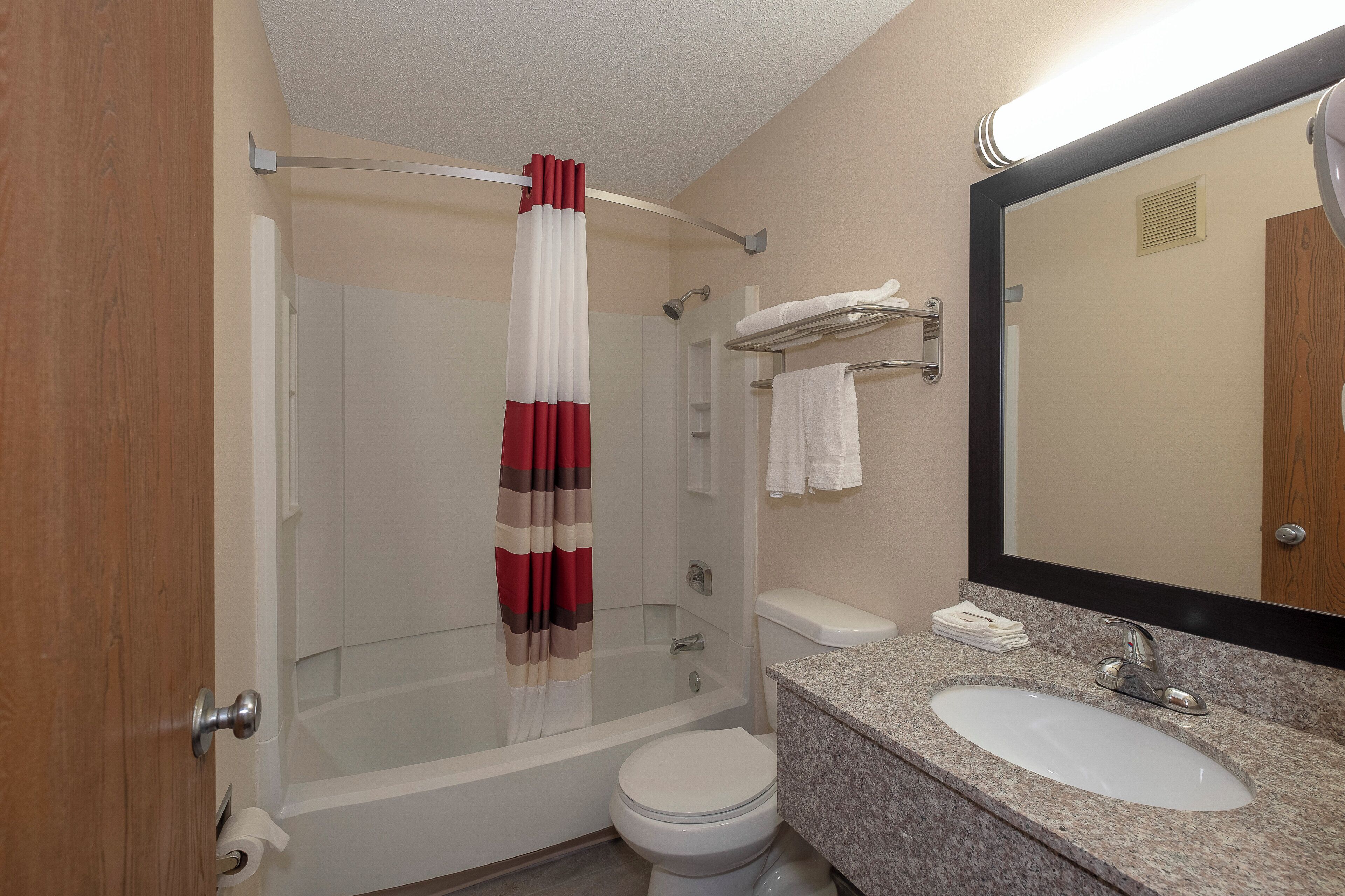 A bathroom with a glass-enclosed shower, a toilet, a sink, and a mirror.