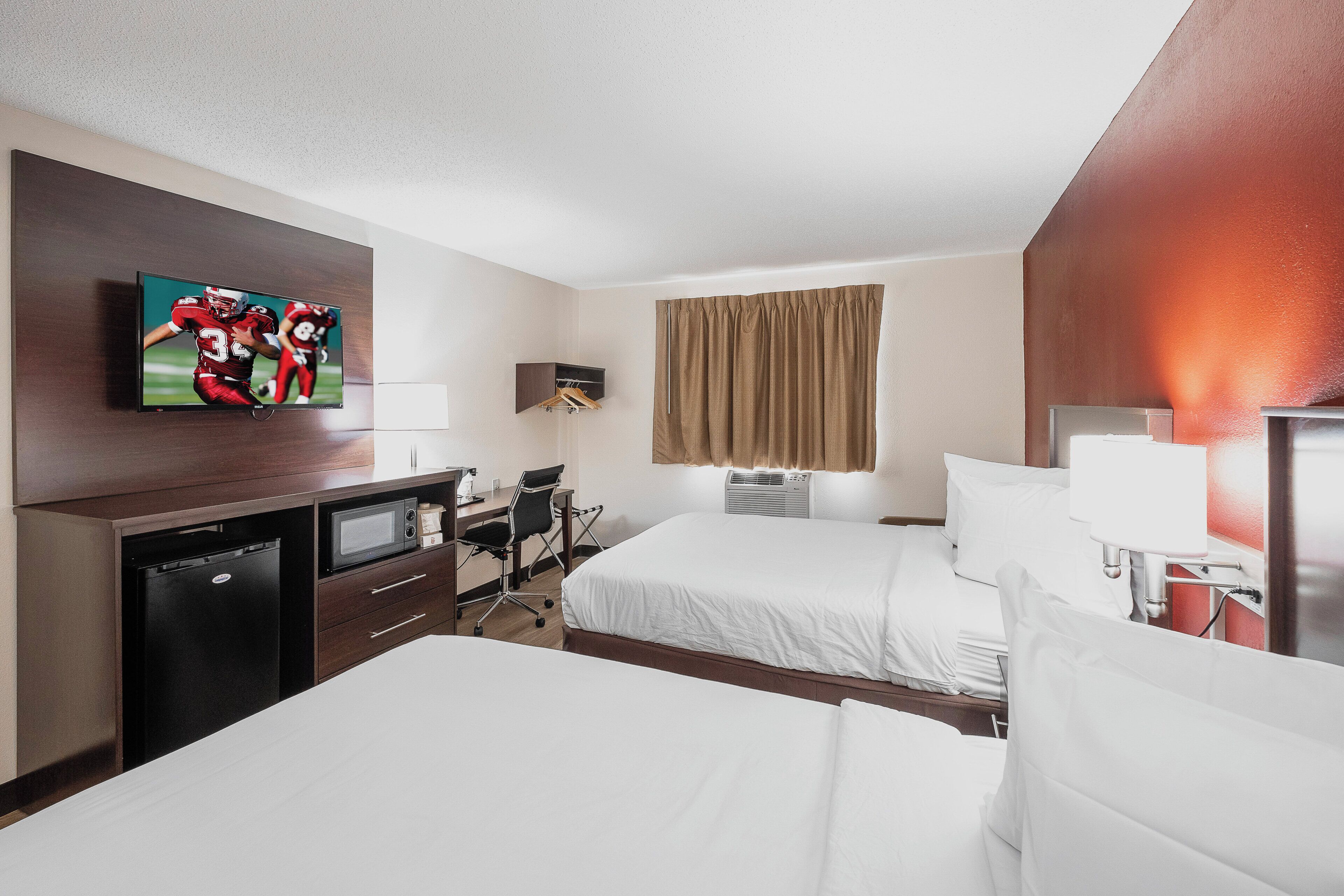 A hotel room with a bed, a desk, a television, and a wardrobe.