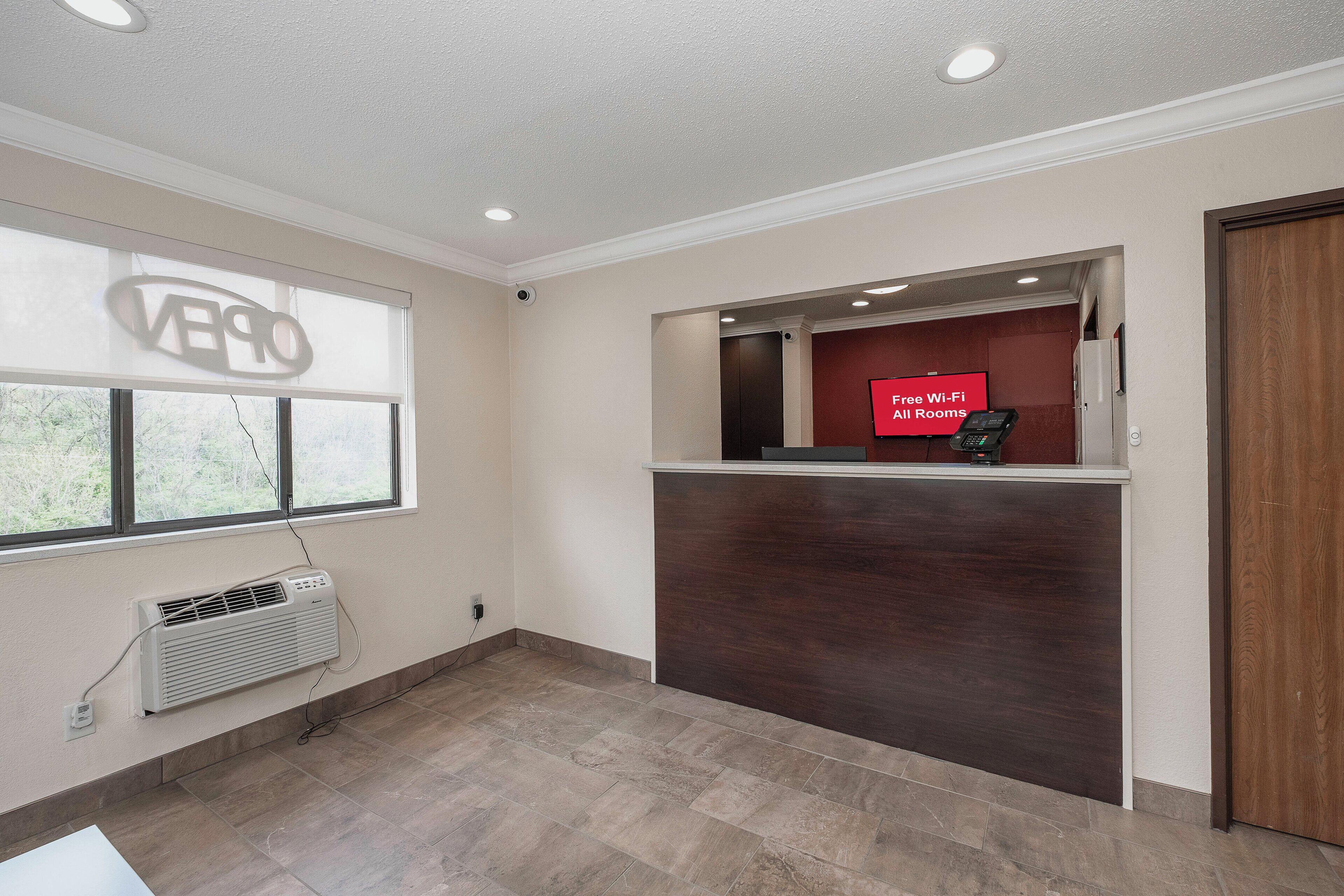 A hotel reception area with a large window, a reception desk, and a sign indicating free Wi-Fi availability.