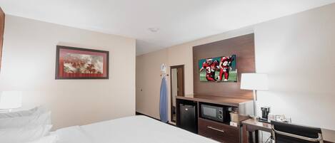 Una habitación de hotel con cama, escritorio, televisor y microondas.