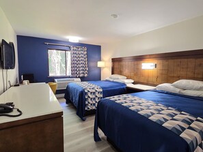 A hotel room with two beds, a desk with a telephone, a window with curtains, and a wall-mounted TV. - Economy 7 Inn - Chesapeake/Portsmouth (Chesapeake)