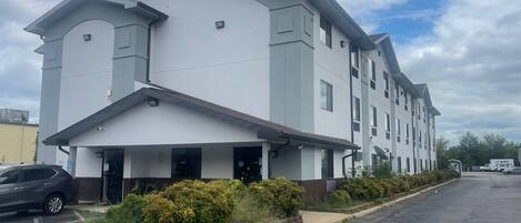 A modern multi-story building with a flat roof, large windows, and a covered entrance area.