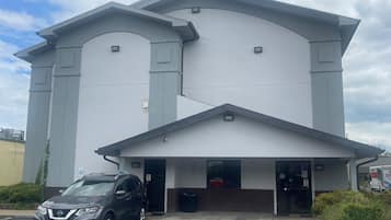 A modern building with a flat roof and two entrances. A car is parked in front.